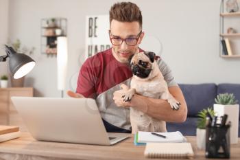 Handsome man with cute pug dog and laptop at home�