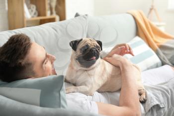 Handsome man with cute pug dog at home�