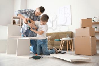 Father and his little son assembling furniture at home�