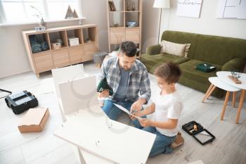 Father and his little son assembling furniture at home�