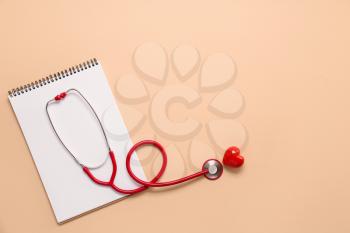 Stethoscope, notebook and red heart on color background. Cardiology concept�