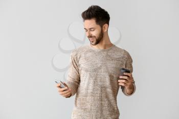 Happy young man with mobile phone on grey background�