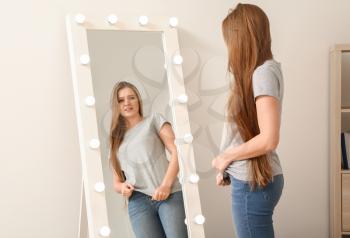 Displeased young woman near mirror at home�