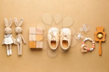 Baby booties with toys on color background�
