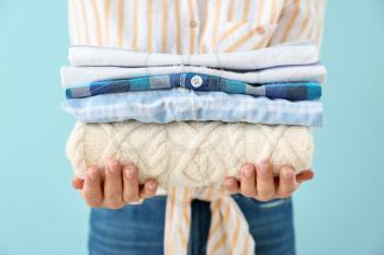 Young woman with clean laundry on color background, closeup�