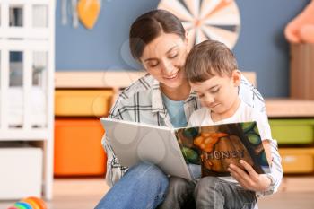 Nanny and cute little boy reading book at home�