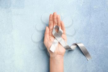 Female hand with Parkinson's awareness ribbon on color background�