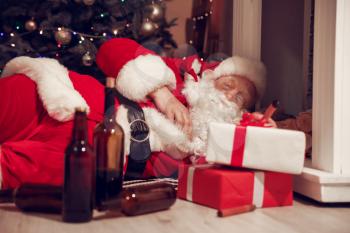 Funny drunk Santa Claus lying on floor near fireplace�