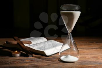 Hourglass, Bible and cross on wooden background�