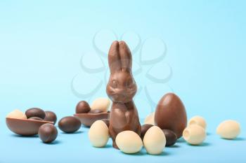 Chocolate Easter eggs and bunny on color background�