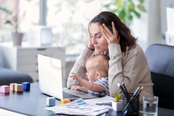 Stressed mother with her baby working in office�