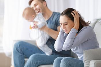 Happy father with his baby and wife suffering from postnatal depression at home�