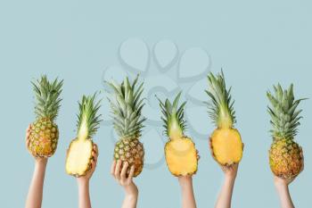 Hands with juicy pineapples on color background�