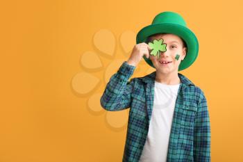 Funny little boy with clover on color background. St. Patrick's Day celebration�