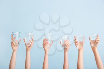 Female hands with glasses of water on color background�