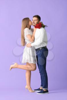 Happy young couple with bouquet of flowers on color background�