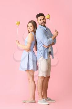 Happy young couple with hearts on color background�