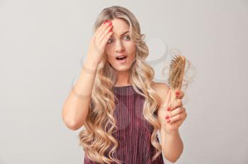 Worried woman with hair loss problem on light background�