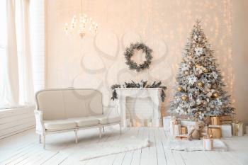 Stylish interior of living room with beautiful Christmas tree and fireplace�