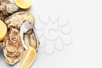 Tasty oysters with lemon on white background�