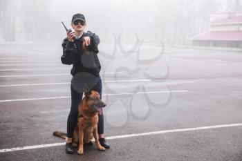Female police officer with dog patrolling city street�