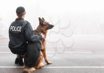 Female police officer with dog patrolling city street�