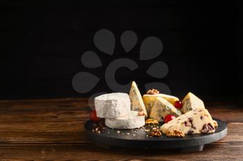 Board with assortment of fresh cheeses on wooden table�