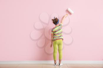 Little girl painting wall in room�
