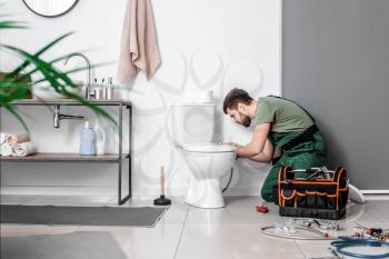 Plumber installing toilet bowl in bathroom�