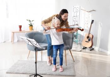 Private music teacher giving violin lessons to little girl at home�
