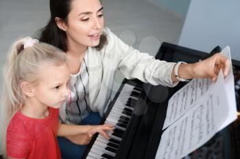 Private music teacher giving piano lessons to little girl�