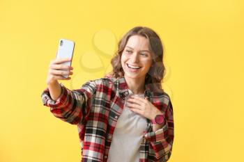 Young woman taking selfie on color background�