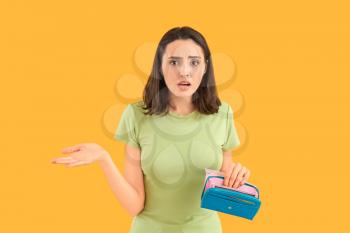 Worried young woman with empty wallet on color background�
