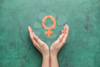 Female hands with symbol of woman on color background. Concept of feminism�