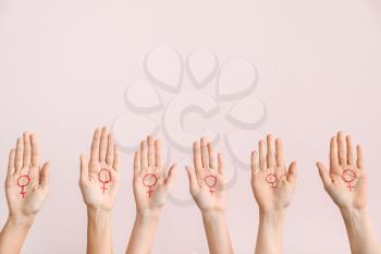 Women with drawn symbols of woman on their palms against color background. Concept of feminism�