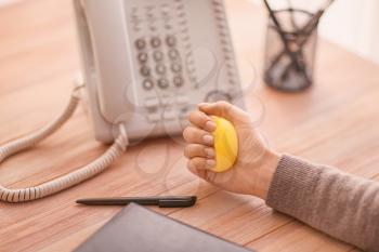 Woman squeezing stress ball while working in office�