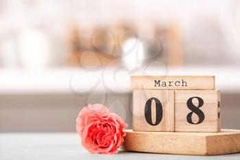 Calendar with date of International Women's Day and flower on table in kitchen�
