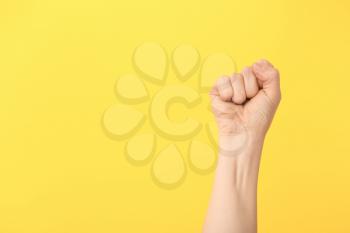 Hand of woman with clenched fist on color background�