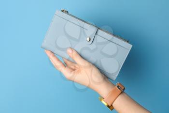 Female hand with wallet on color background�