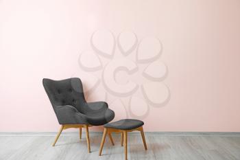 Stylish armchair near color wall in room�