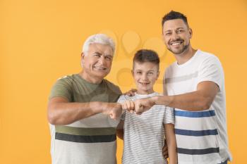 Man with his father and son bumping fists against color background�