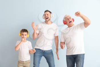Man with his father and son listening to music on color background�
