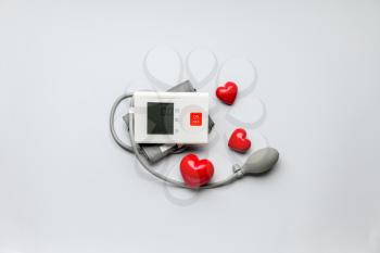 Electronic sphygmomanometer and red hearts on light background 