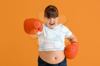 Overweight girl with boxing gloves on color background�