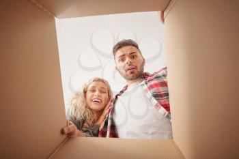 Emotional young couple with open moving box, view from inside�