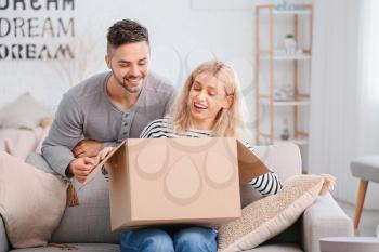 Happy young couple unpacking box at home�