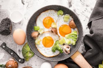 Frying pan with cooked eggs and vegetables on white background�