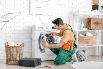 Worker repairing washing machine in laundry room�