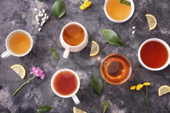 Cups with different types of hot tea on dark background�