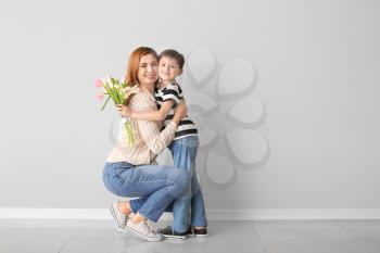 Little boy greeting his mother against light wall�